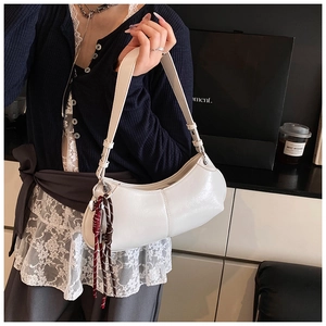 Detailed texture of white leather hobo bag with a decorative woven brown tassel charm