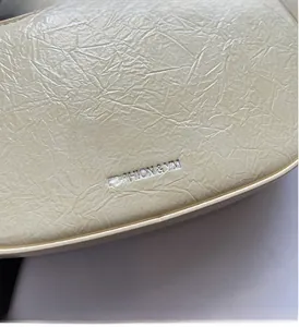 Macro shot of crinkled cream faux leather texture with Fashion & YM stamped logo