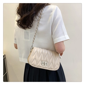 Detail of cream quilted chain shoulder bag with diamond-studded metallic twist lock