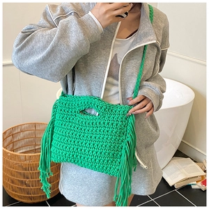 Detail der hellgrünen Häkeltasche mit grober Strickstruktur und seitlichen Quasten