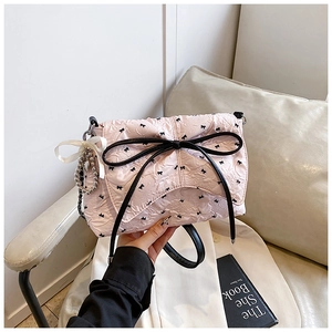 Detalle del bolso de hombro rosa claro con estampados de mariposas y un gran lazo