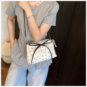 Detalle de bolso acolchado blanco con estampados de lazos negros y lazo grande decorativo