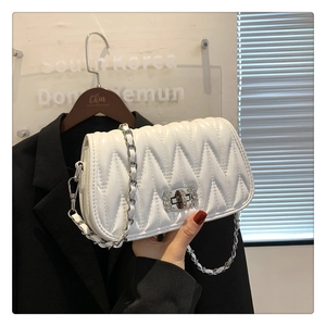 Close-up of white quilted leather shoulder bag with silver chain strap and twist lock