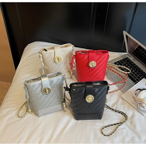Detailed view of woven bucket bags in four colors with gold rotary locks and chain straps
