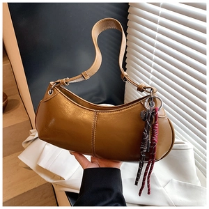 Detail view of a brown crescent shoulder bag with colorful woven tassel decoration