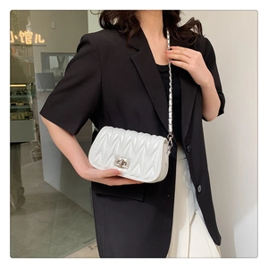 Detail of ivory pleated shoulder bag with silver chain strap and twist-lock closure
