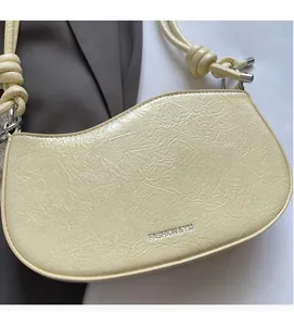 Detailed close-up of cream yellow shoulder bag with pleated texture and silver logo