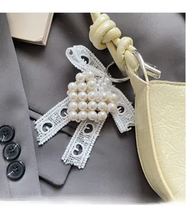 Close-up of heart-shaped pearl bag charm with elegant white lace ribbon and metal ring