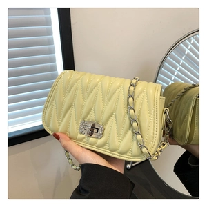 Detail of yellow matelassé handbag with silver chain and rhinestone twist lock