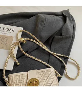 Detail view of woven cream bucket bag with gold chain strap and turn-lock closure