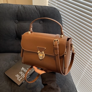 Brown leather crossbody bag with golden twist lock and decorative side zippers for women