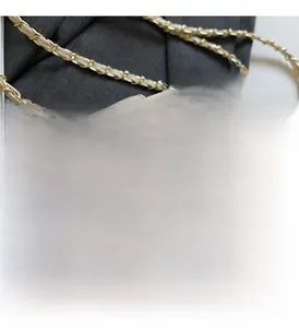 Detail of woven beige leather texture with gold metal rotary lock and chain strap