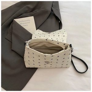 Bolso de mano crema con textura plisada y lazos negros para un estilo casual chic
