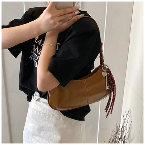 Detail of a brown crescent shoulder bag with glossy leather and heart-shaped charms