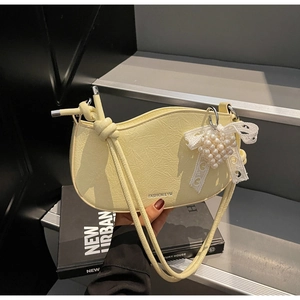 Detail view of yellow faux leather handbag with pearl heart charm and lace bow decor
