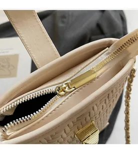 Detail of golden zipper and woven texture on a beige minimalist chain bucket bag