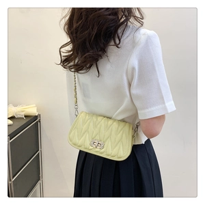 Detail of light green ruched leather shoulder bag with rhinestone clasp worn by a model