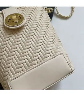 Detail of woven texture small bucket bag with gold clasp and chain strap