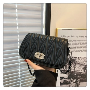 Close-up of black quilted matelassé leather shoulder bag with crystal twist lock and chain