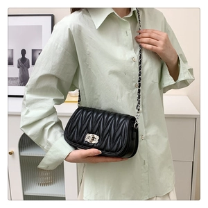 Detail of black quilted leather crossbody bag with chain strap and metallic lock closure