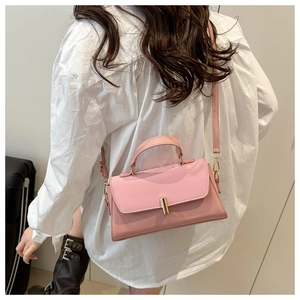 Pink minimalist crossbody bag with gold metal lock worn by a model in a street style shot