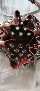 Detailed top view of wine red patent leather bucket bag with silver metal eyelets