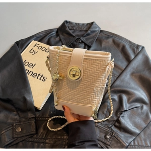 Detail of beige woven bucket bag with gold chain strap and metallic twist lock clasp