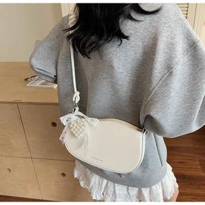 Close-up of cream white PU handbag with lace bow and pearl heart pendant detail