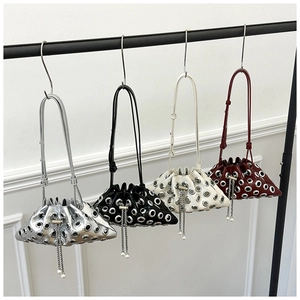 Detail view of four studded bucket bags in silver black white and burgundy on a rack