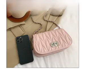 Pink quilted chain crossbody bag shown with a smartphone for size scale comparison