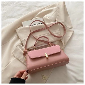 Detailed view of a pink structured handbag with gold metallic clasp on a white blazer