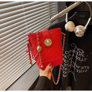 Detail of red woven bucket bag featuring gold metal rotary lock and chain strap