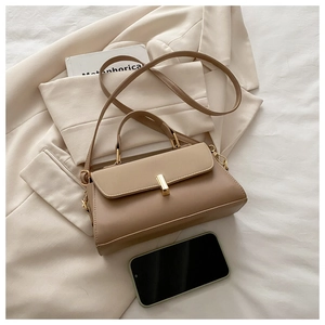 Detail of minimalist two-tone leather crossbody bag with golden twist lock on a blazer