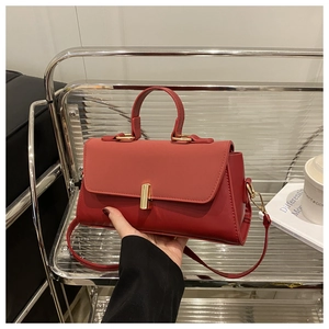 Detailed view of the red leather handbag with gold cylindrical metal lock and handle