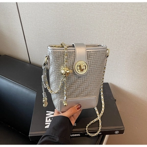 Close-up of silver woven bucket bag with gold clasp and metallic ball chain detail