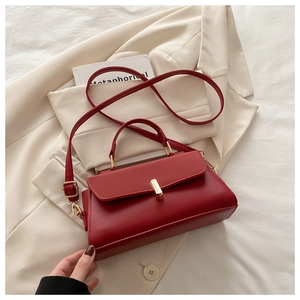 Detail of dark red leather handbag with gold twist lock and adjustable shoulder strap