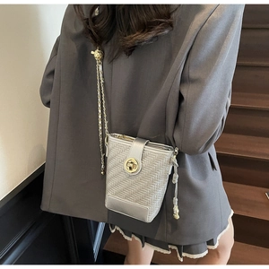 Detail view of woven silver crossbody bag with golden chain and metallic clasp