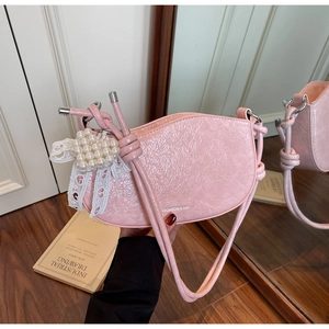 Detail of pink crescent bag with glossy wrinkled leather and pearl heart bow charm