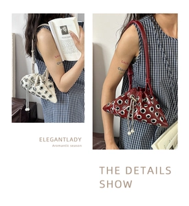 Detail of studded bucket bag with silver eyelets and pearl chain tassel in dual colors