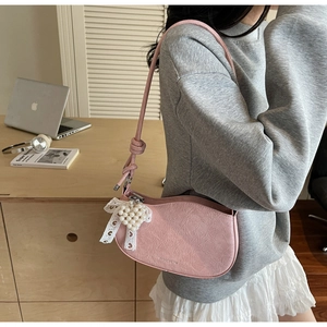 Detail of pink crescent bag with pleated faux leather, white lace bow, and pearl heart charm