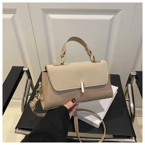 Close-up of beige faux leather handbag with golden cylindrical clasp and top handle