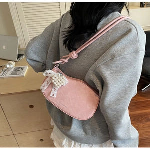 Detail of pink faux leather bag with lace bow and pearl heart pendant on desk