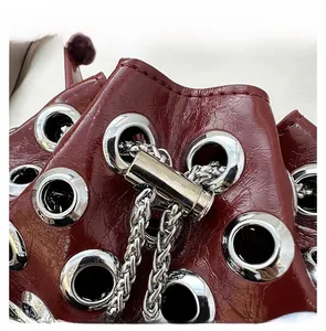 Macro detail of wine red patent leather bucket bag with silver metal eyelets and chain lock