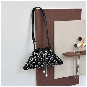 Detailed shot of black leather bucket bag with silver metal eyelets and pearl chain