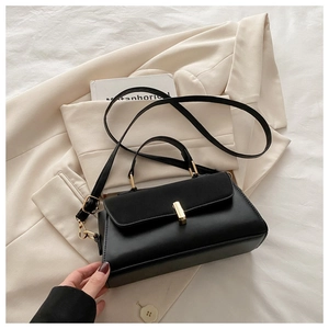 Detail of a black matte leather handbag with gold metal lock and adjustable shoulder strap