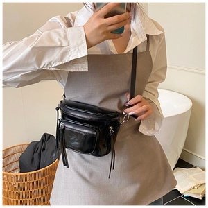Détail du sac bandoulière en PU noir brillant avec poches et fermetures à franges