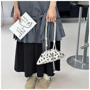 Close-up of white bucket bag featuring silver grommets and pearl drawstring detail
