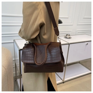 Detail of dark brown faux crocodile leather tote bag with wide fabric shoulder strap