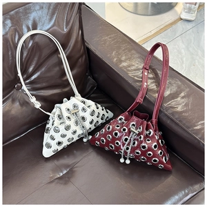 Detail of trendy bucket bag with metal grommets, drawstring closure and pearl chain
