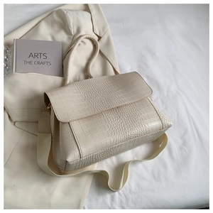 Detail of cream faux crocodile texture handbag with wide fabric shoulder strap and handle